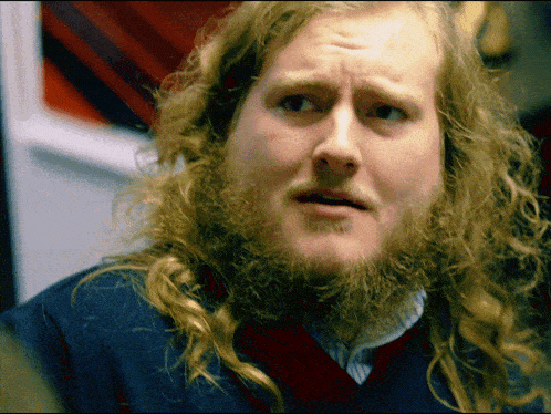 a man with long hair and a beard is making a face