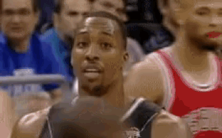 a man in a basketball uniform is standing in front of a crowd of people .