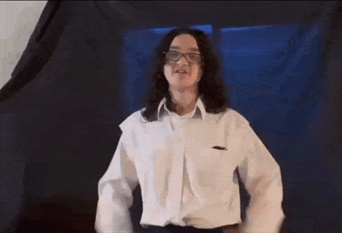 a woman wearing glasses and a white shirt is dancing