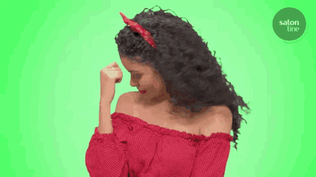 a woman with curly hair is wearing a red off the shoulder top