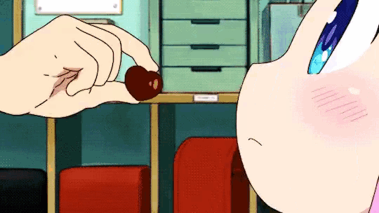 a person is holding a heart shaped object in their hand while another person looks on .