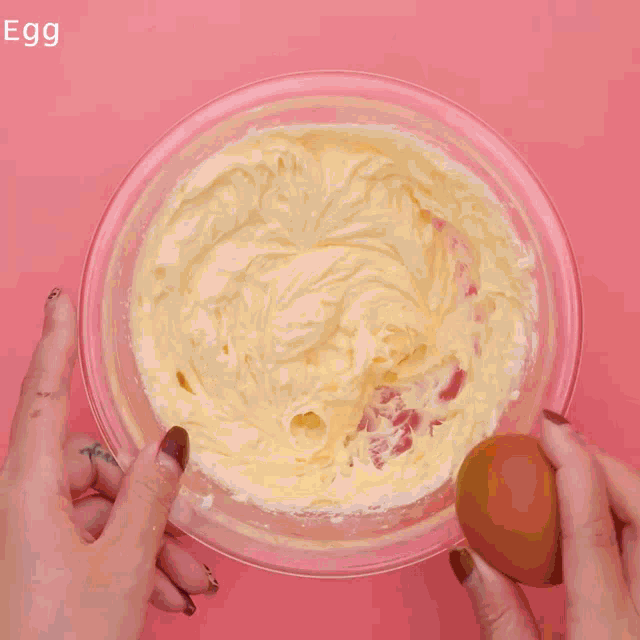a bowl filled with crumbs on a pink background