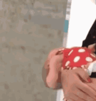 a baby is being held by a person in a red and white polka dot dress .