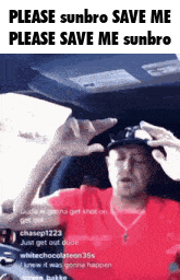 a man in a red shirt is sitting in a car holding his hand to his head .