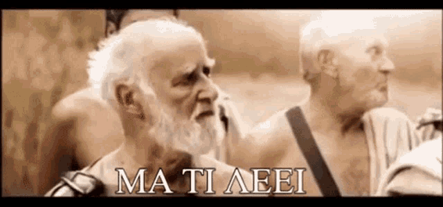 a man with a beard is standing next to another man with the words mati aeei on the bottom .