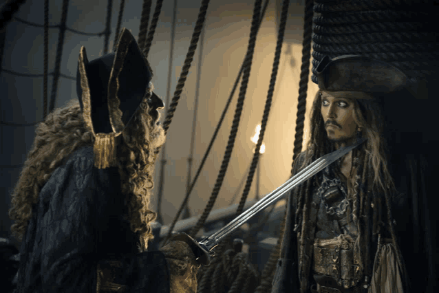 a man in a pirate costume holds a sword and talks to another man