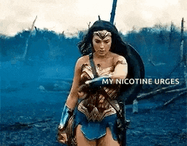 wonder woman is standing in the middle of a field holding a shield and a gun .