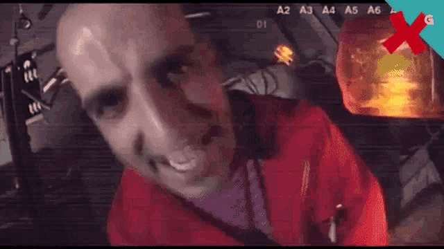 a man in a red jacket is looking at the camera with a bullet in his head