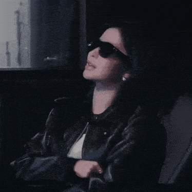 a woman wearing black sunglasses and a leather jacket