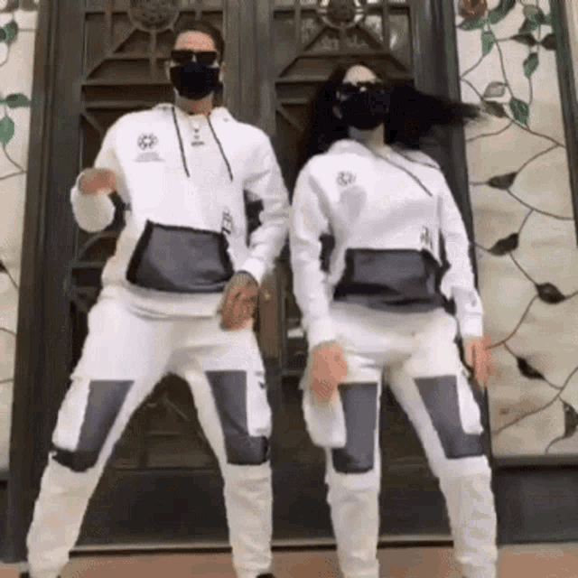 a man and a woman wearing face masks are dancing in front of a stained glass door .