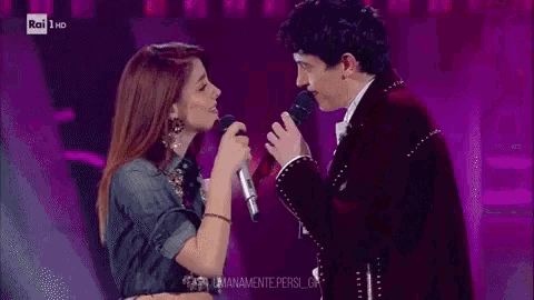 a man and a woman singing into microphones on a stage with the words rai 1 hd in the corner