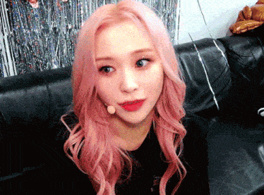 a woman with pink hair sitting on a couch