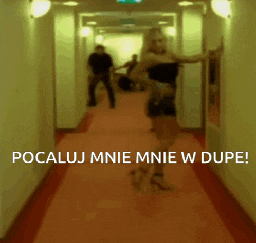 a blurred image of a woman dancing in a hallway with the words pocaluj mnie mnie w dupe below her