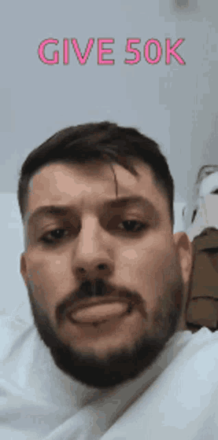 a man with a beard is making a funny face with the words give 50k written above him .