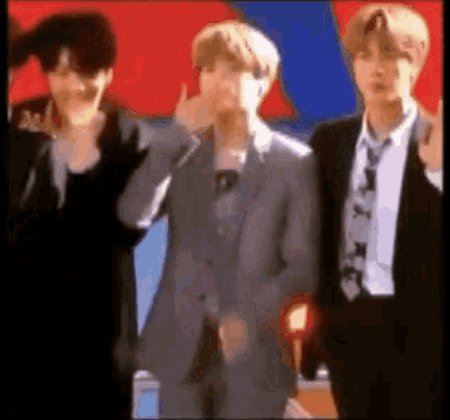 three men in suits and ties are standing next to each other and making funny faces .