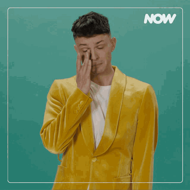 a man in a yellow suit is covering his face and the word now is on the bottom