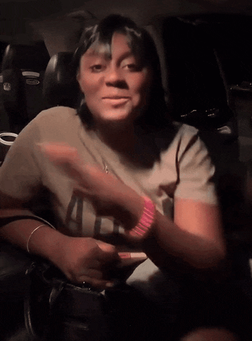 a woman sitting in the back seat of a car wearing a t-shirt that says i 'm a nurse