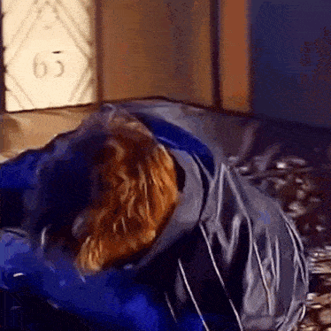 a man in a blue jacket is laying on a couch .