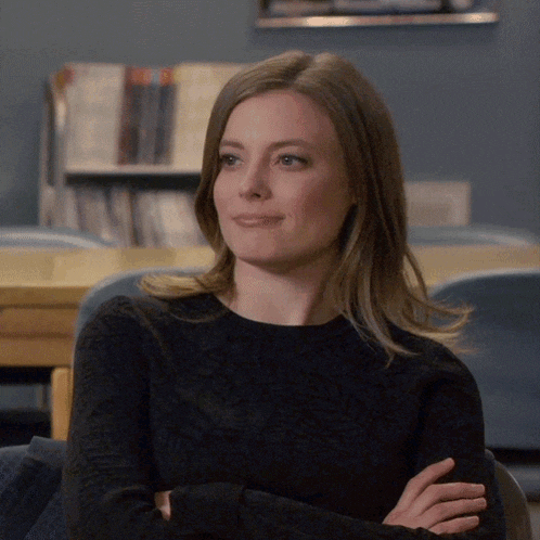 a woman in a black sweater is sitting with her arms crossed and smiling