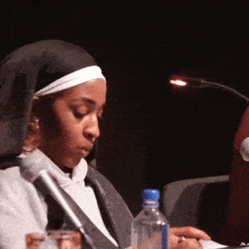 a nun sits at a table with a bottle of water