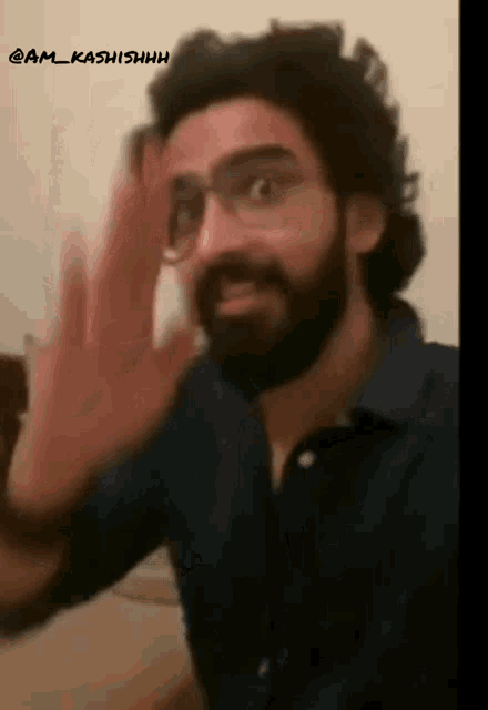 a man with glasses and a beard is waving