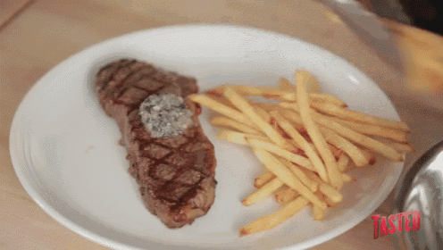 a white plate with a steak and french fries has the word taster in red