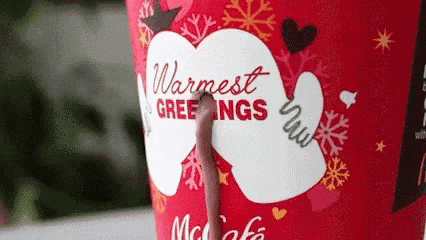 a close up of a cup of hot chocolate with the words `` warmest greetings '' written on it .