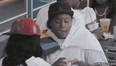 a group of people are sitting at a table eating hamburgers and drinking milkshakes .