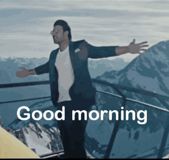 a man is standing on a balcony with his arms outstretched and the words " good morning " below him