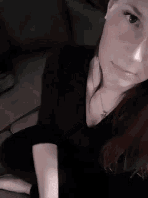 a woman is sitting on a couch and taking a selfie with her phone .