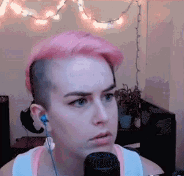 a woman with pink hair is wearing ear buds and a microphone