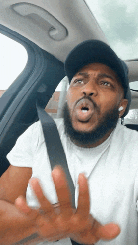 a man with a beard wearing a hat and a seat belt making a funny face
