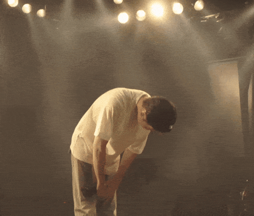 a man singing into a microphone with a thank you sticker underneath him