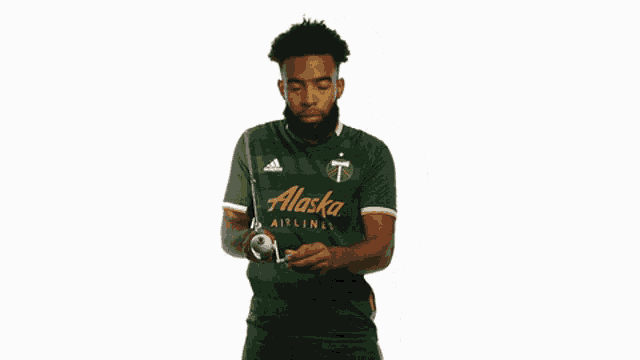 a man in a green alaska airlines jersey holds a stick
