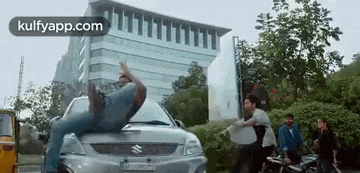 a man is standing on the hood of a car .