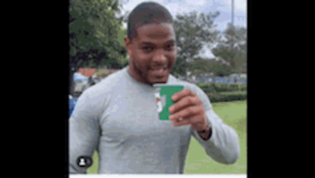 a man in a gray shirt is holding a green cup in his hand .