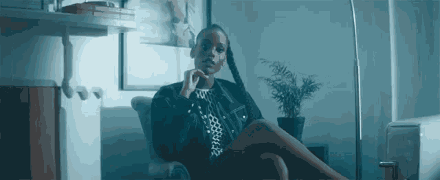 a woman in a black jacket sits in a chair