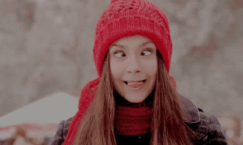 a woman wearing a red hat and scarf making a funny face .