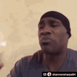 a man wearing a hat and a gray shirt is making a funny face .