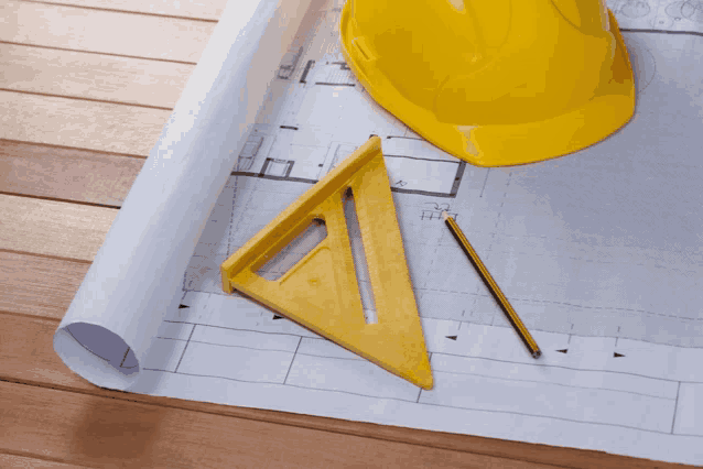 a yellow hard hat sits next to a yellow triangle and a pencil