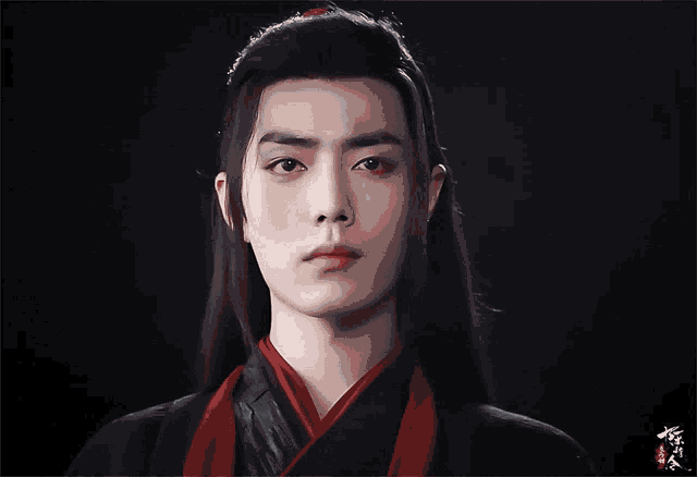 a man with long black hair and a red scarf