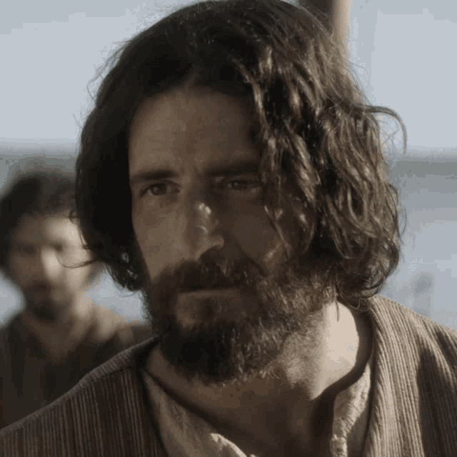 a man with long hair and a beard looks serious
