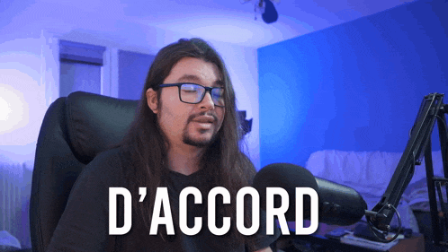 a man with long hair and glasses is sitting in front of a microphone with the word d' accord on the screen