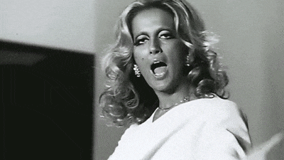a black and white photo of a woman singing into her mouth
