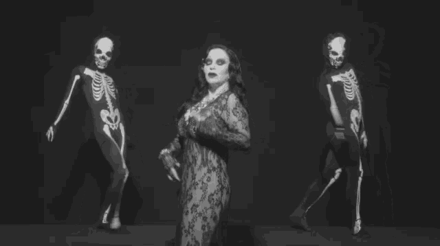 a woman in a lace bodysuit is surrounded by skeletons in black and white