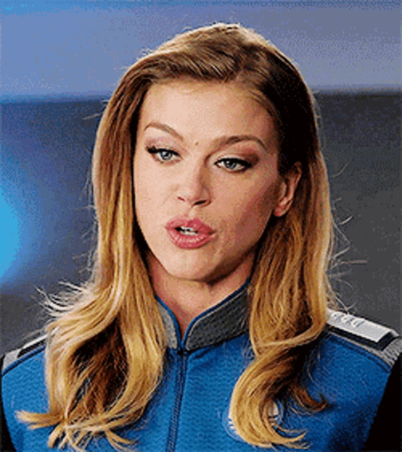 a woman in a blue jacket is making a face