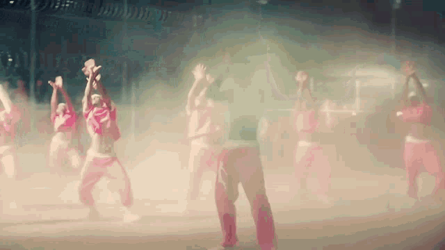a group of people are dancing in a dark room with smoke coming out of it
