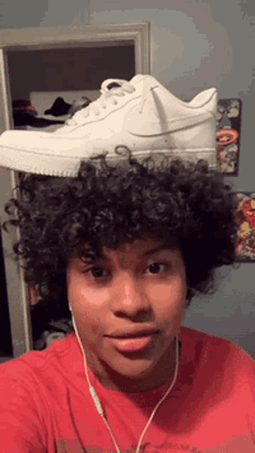a person with curly hair has a white nike shoe on their head