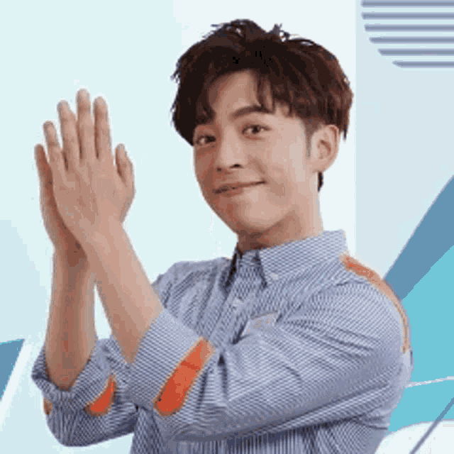 a young man in a blue and white striped shirt is clapping his hands together .