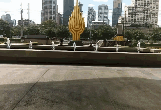 a fountain in front of a city with a statue in the background